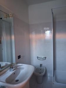 La salle de bains blanche est pourvue d'un lavabo et de toilettes. dans l'établissement Signorile quadrilocale nel verde di Villa Guardia, à Villa Guardia