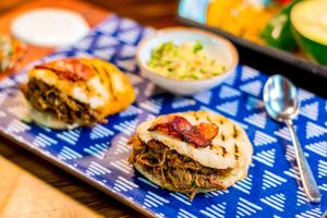 a blue tray with two sandwiches and a bowl of coleslaw at Rancho Ton Hotel Boutique in Santa Marta