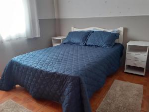 a bed with a blue comforter in a bedroom at Casa/chale Campos do Jordao in Campos do Jordão