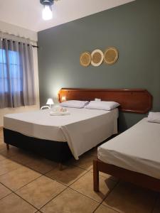 een slaapkamer met twee bedden met hoeden aan de muur bij Hotel Aurora in Olímpia