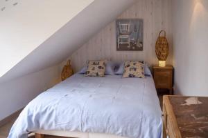 um quarto com uma cama branca com almofadas e uma cadeira em Le Nid em Lanloup
