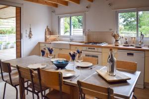 uma cozinha com uma mesa e cadeiras de madeira, uma mesa e uma espreguiçadeira em Le Nid em Lanloup
