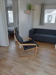 a living room with a chair and a couch at Stacaravan Bredene met tuin nr 2126 in Bredene