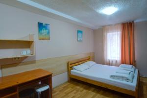a small bedroom with a bed and a desk at Hostel Podolski Plus in Kyiv