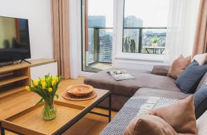 a living room with a couch and a table with flowers at Klingerka residence 20th floor castle view Free parking and Wi-Fi in Bratislava