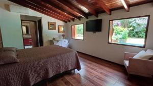 1 dormitorio con 1 cama, 1 silla y 2 ventanas en Sítio Encontro das Águas Brotas, en Ibirapuera