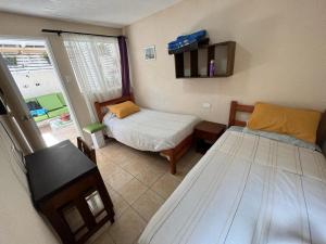 Habitación pequeña con 2 camas y ventana en Hostal del Rosario La Serena en La Serena