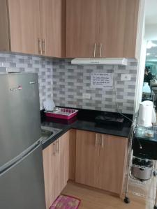 a kitchen with wooden cabinets and a stainless steel refrigerator at 2 BR Loop Tower 1524 in Cagayan de Oro