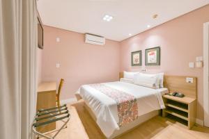 a bedroom with a large white bed and pink walls at Araçatuba Plaza Hotel in Araçatuba