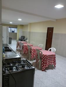 a kitchen with tables and chairs and a stove at Pousada caminho das praias jp in João Pessoa