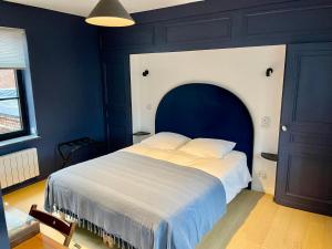 a bedroom with a large bed with a blue wall at LA PARCELLE in Lezennes