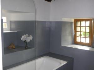 ein Badezimmer mit einer Badewanne und einer Vase aus Blumen in der Unterkunft Les Gites de TY Dreux Monts d'arrée in Saint-Thégonnec