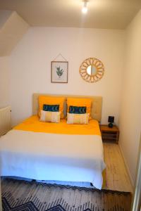 1 dormitorio con 1 cama grande con almohadas de color naranja en Logement cozy proche du centre-ville, en Poitiers