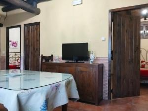 ein Wohnzimmer mit einem Tisch und einem TV in der Unterkunft Casa Rural Josefina 1 y 2 in Navaconcejo