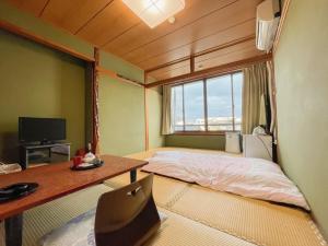 a room with a bed and a desk and a window at Eimiya Ryokan - Vacation STAY 36252v in Amakusa