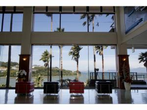 Hotel Alegria Gardens Amakusa - Vacation STAY 40453v في أماكوسا: لوبي فيه نخيل ومطل على المحيط