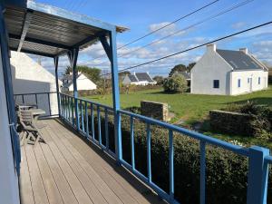 une terrasse couverte avec une balustrade bleue et une maison blanche dans l'établissement Ty Kellen, à Groix