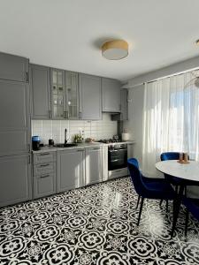 a kitchen with white cabinets and a table with chairs at Cloos - Elegant Residence with Panoramic View in Braşov