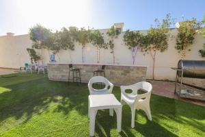 dos sillas blancas sentadas en el césped en un patio trasero en La bonita compound, en Hurghada