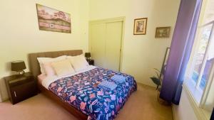 una camera da letto con un letto con copriletto floreale e una finestra di The Garden Cottage a Tawonga