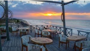 ein Restaurant am Strand mit Tischen und Stühlen in der Unterkunft Mar Azul - Playa y Turismo in Camarones