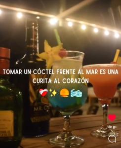 due bicchieri seduti su un tavolo con una bottiglia di vino di Mar Azul - Playa y Turismo a Camarones