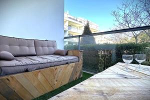 un sofá y dos copas de vino en el patio en L'Odyssée-Appart au calme avec balcon et parking en Nantes