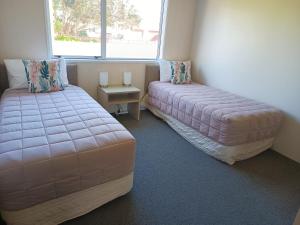 1 dormitorio con 2 camas y ventana en Beaches Motel, en Waihi Beach