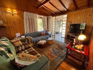 a living room with a couch and a tv at Recanto Habacuque in Campos do Jordão