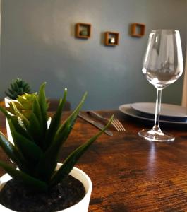 uma mesa de madeira com um copo de vinho e um vaso de plantas em Le Donatien-Cosy appart proche centre et Erdre em Nantes