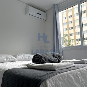 1 dormitorio con 1 cama con manta y ventana en Hotel Lara 10 Curitiba en Curitiba