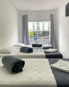 3 camas en una habitación con ventana en Hotel Lara 10 Curitiba en Curitiba