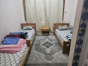 Cette chambre comprend 2 lits et un tapis. dans l'établissement بيت الشباب 22 فبراير ورقلة, à Bordj Lutaud
