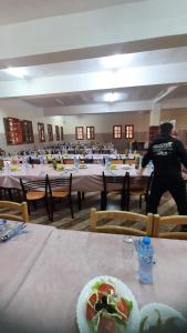 un homme debout devant une pièce avec des tables dans l'établissement بيت الشباب 22 فبراير ورقلة, à Bordj Lutaud