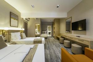 a hotel room with two beds and a flat screen tv at Hotel Kalfa in Trabzon