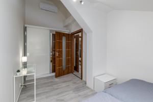 een witte slaapkamer met een bed en een spiegel bij Apartment Cimburkova in Praag