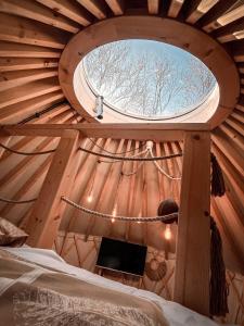 uma janela redonda num quarto de madeira com uma cama em Aloha Glamp - Domki z prywatnym jacuzzi & balia & sauna em Zagórnik