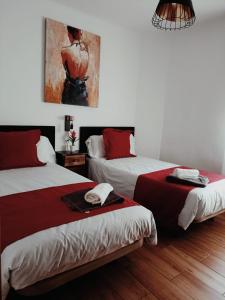 マドリードにあるCasa Cobo Exclusivo Alojamiento en Madridのベッド2台が備わる客室で、壁には絵画が飾られています。