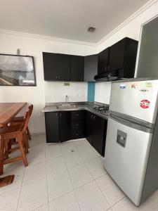 uma cozinha com electrodomésticos a preto e branco e uma mesa em AW Hotel Rodadero Suites em Santa Marta