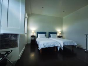 um quarto com 2 camas com lençóis brancos e 2 candeeiros em Quinta São José da Relva em Ponta Delgada