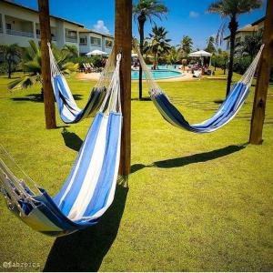 duas redes de descanso azuis e brancas num parque com piscina em Apartamento Master VIP com 3 suítes noTree Bies Resort em Subaúma