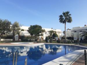 a large swimming pool with palm trees and buildings at apartamento playa in Isla Cristina
