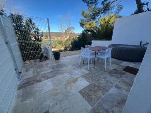 Un patio con mesa y sillas y una valla. en maison t2 avec jaccuzi wifi parking, en Saint-Cyr-sur-Mer
