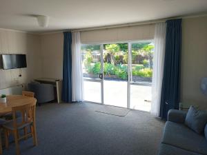 uma sala de estar com uma grande porta de vidro deslizante em Beaches Motel em Waihi Beach