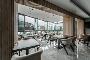un restaurante con mesas, sillas y ventanas grandes en Hotel Kalfa, en Trabzon
