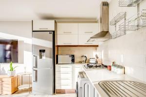 ケープタウンにあるQuayside Canal Eden Homeの白いキャビネットと冷蔵庫のあるキッチン