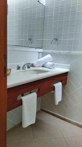 a bathroom with a sink with a mirror and towels at Hotel Dominguez Plaza in Nova Friburgo