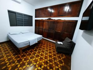 um quarto com uma cama e uma cadeira em Ritz Hostel em Araçatuba
