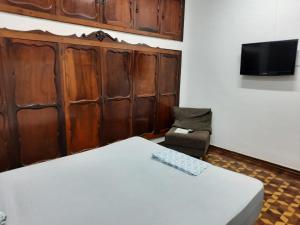 Habitación con cama, silla y TV. en Ritz Hostel, en Araçatuba