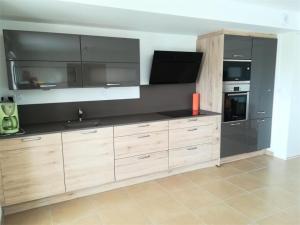 a kitchen with wooden cabinets and a black appliances at Résidence Coteau - Charmant appartement de 70m² dans une résidence à deux pas de la plage. MAE-6584 in Pléneuf-Val-André